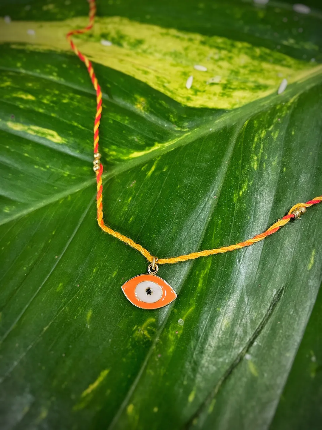 Fancy Orange Evil Eye Charm Designer Rakhi With Multicolored Thread For Raksha Bandhan Celebration